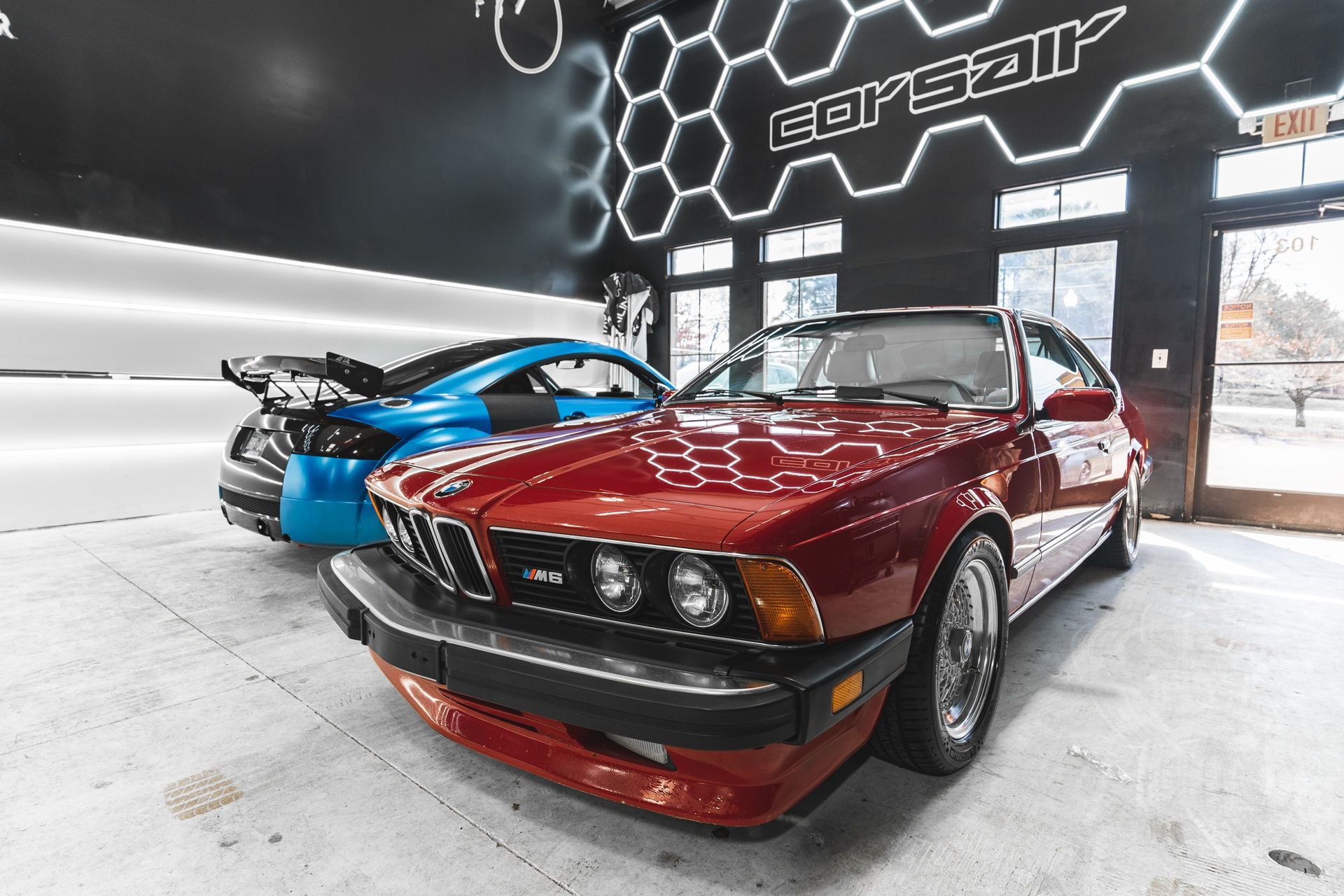 A red car is parked next to a blue car in a garage.