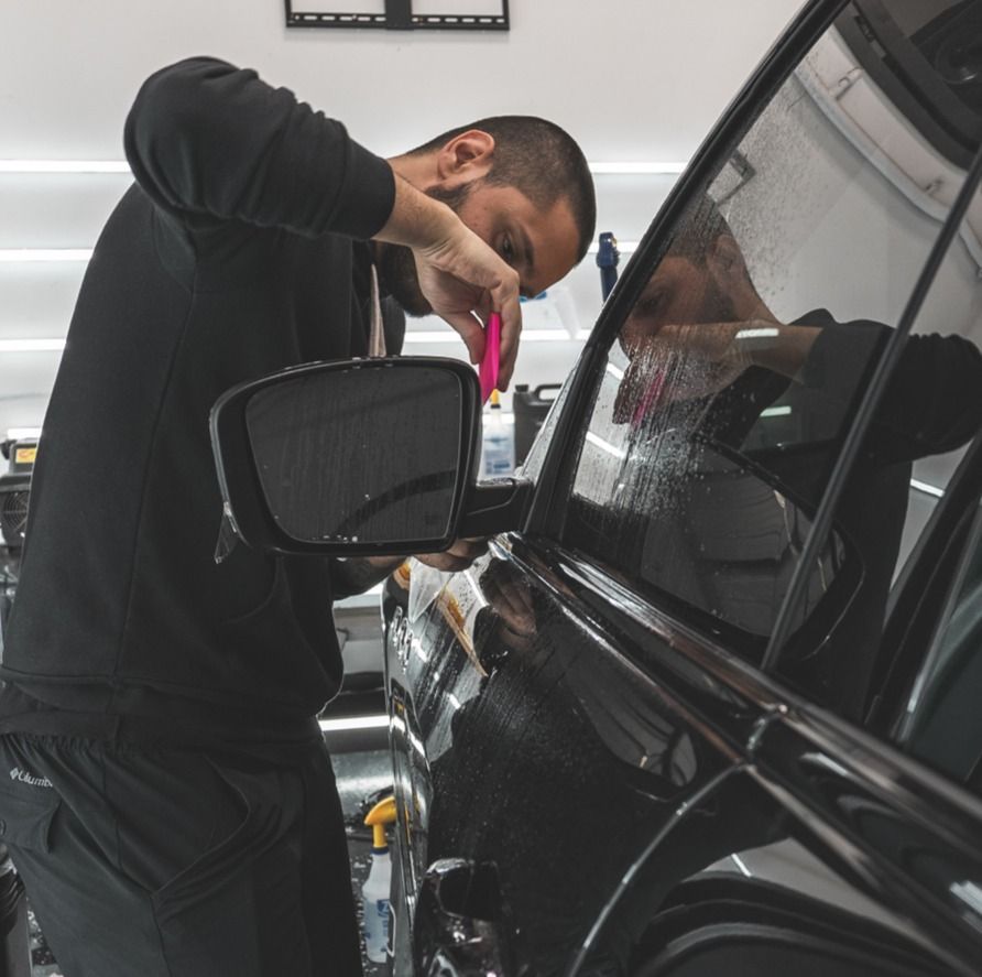 A man in a black shirt is working on a black car