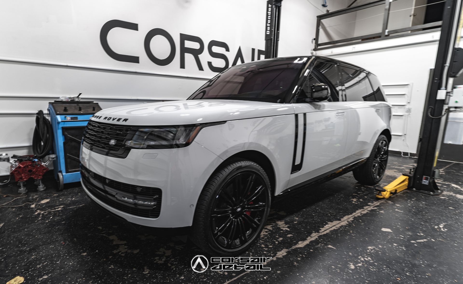 A white range rover is parked on a lift in a garage.