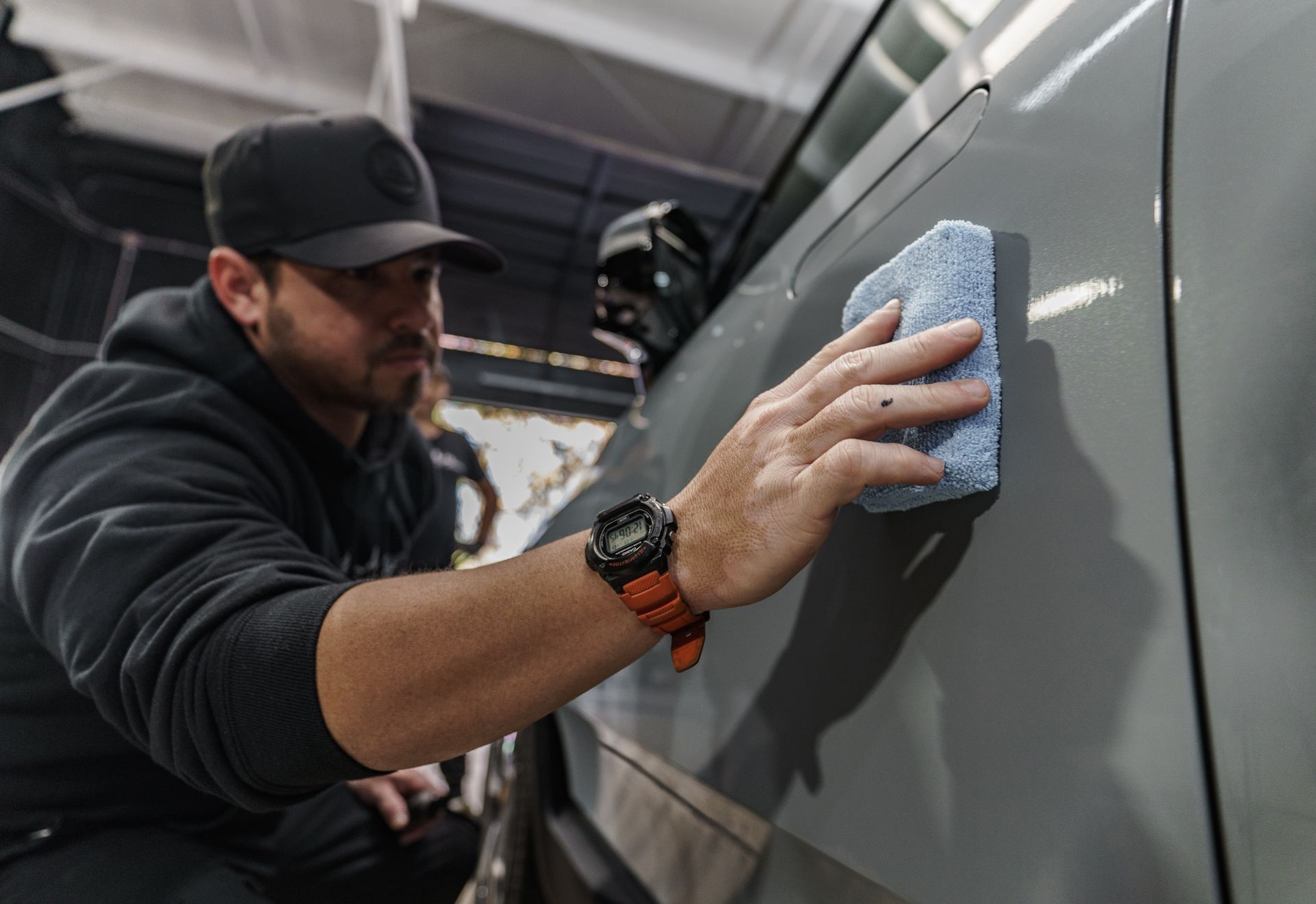 A man is cleaning a car with a sponge.