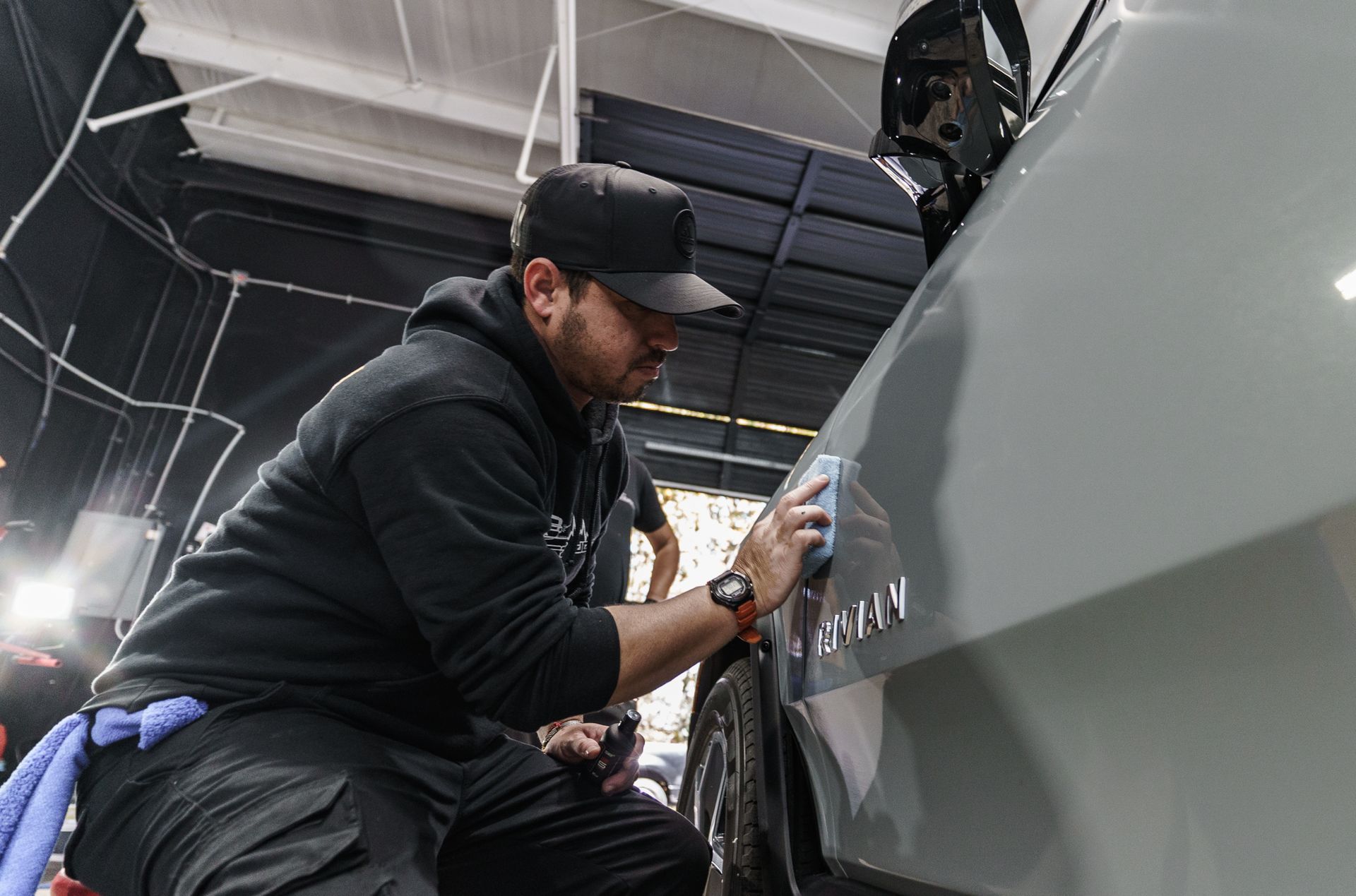 A man is cleaning the side of a car with a cloth.