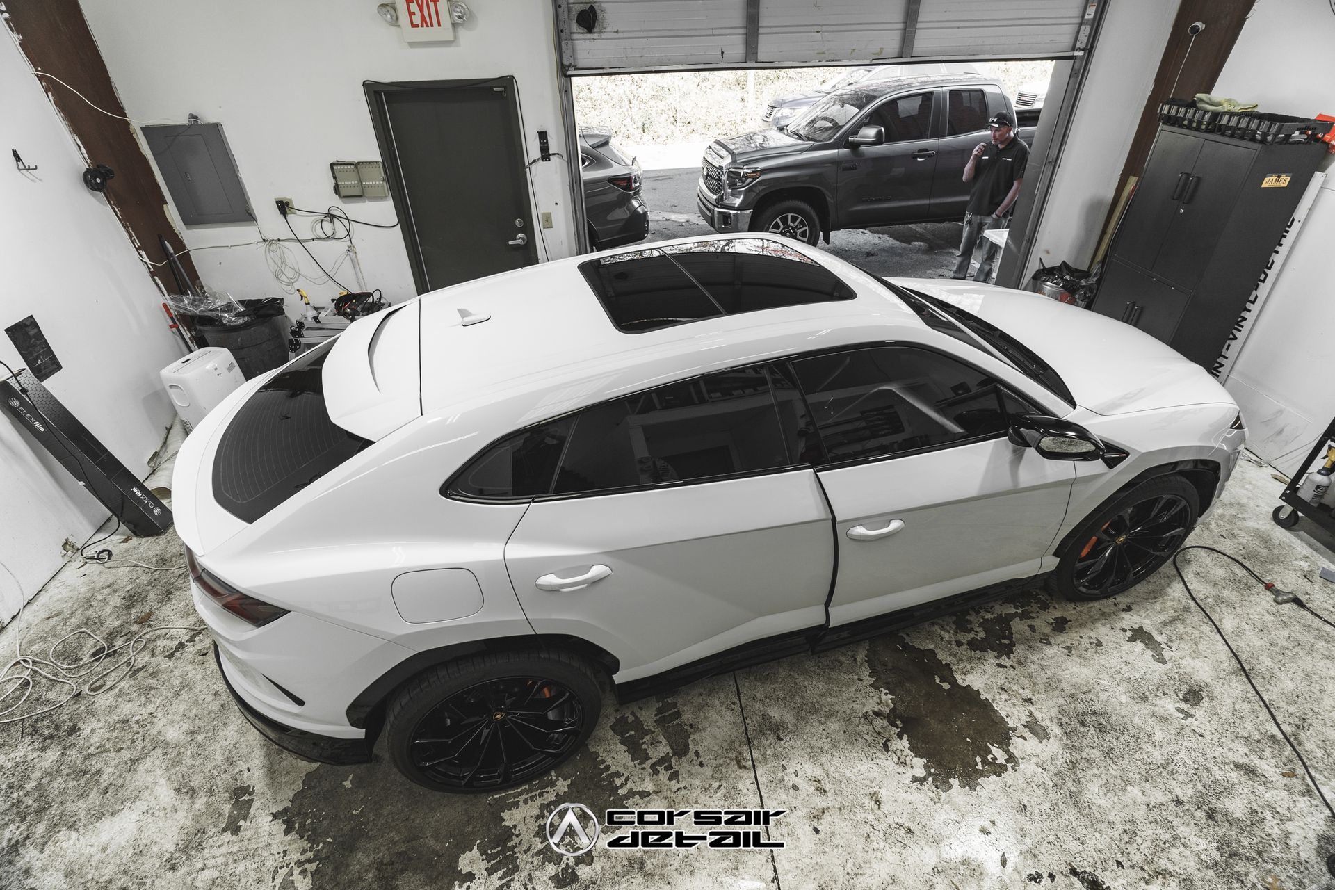 A white car is parked in a garage with a sunroof.