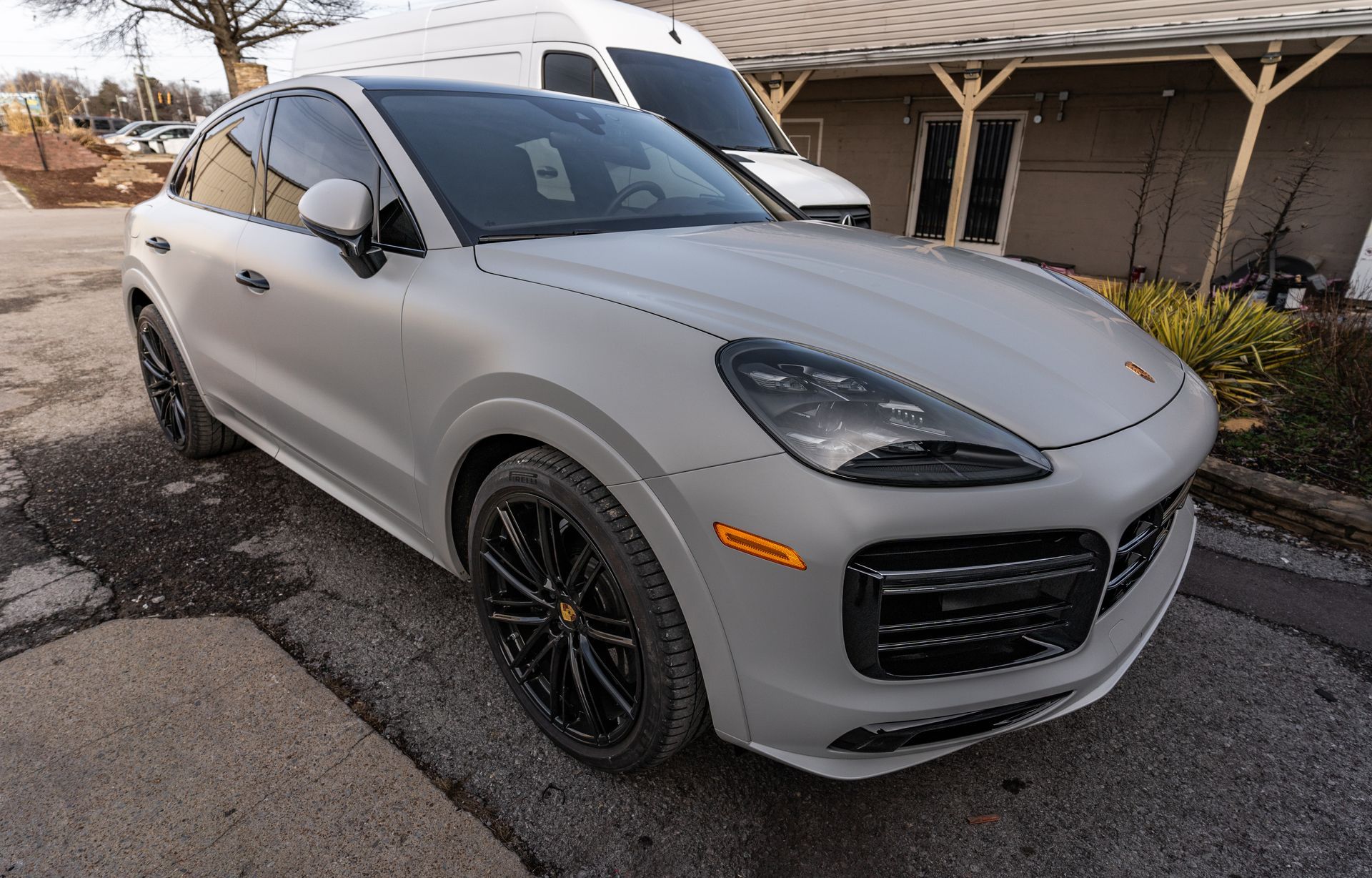 A silver porsche cayenne turbo is parked in front of a building.