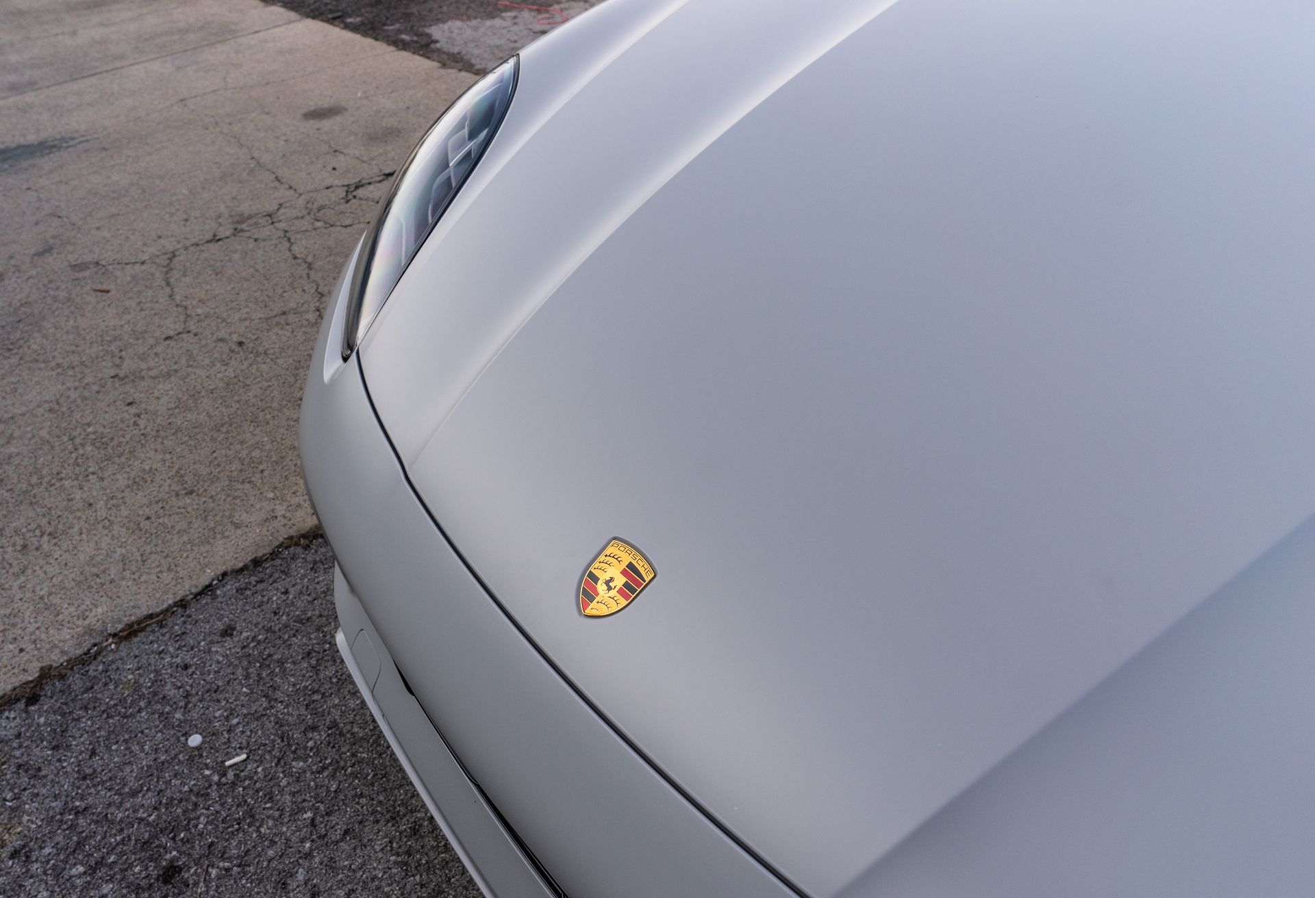 A silver porsche is parked on the side of the road