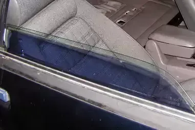 A close up of a car window with a seat in the background.