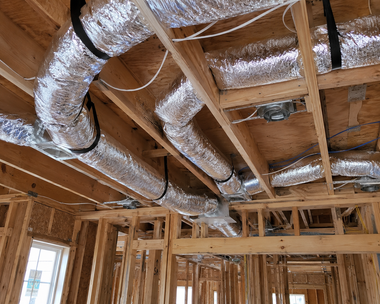 Exposed HVAC ducts and wooden framing in an unfinished house ceiling