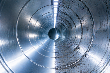 Close-up of a metallic industrial pipe interior with concentric rings and reflective blue-gray surfaces
