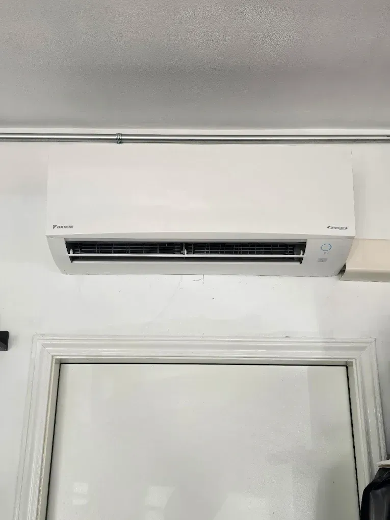 White Daikin wall-mounted air conditioning unit above a white door.