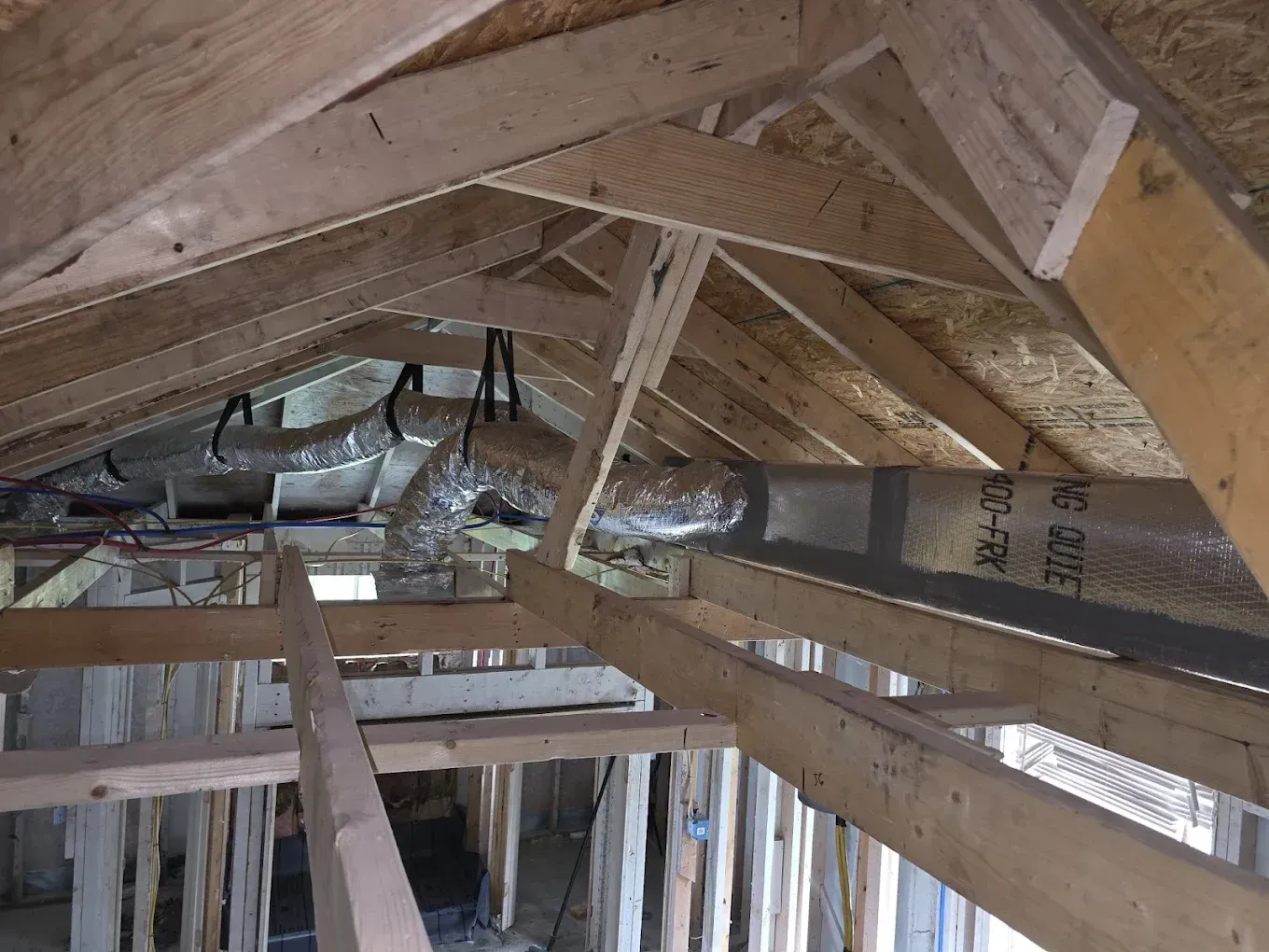 Wooden house frame interior with ductwork in the attic.