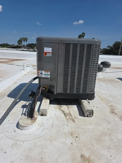 Air conditioning unit on a white rooftop, blue sky in the background.