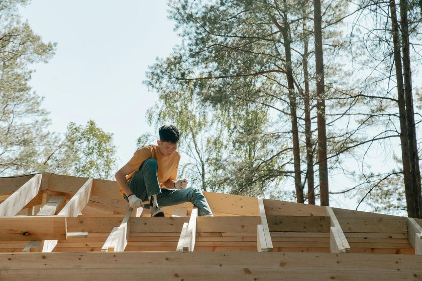 Un homme est assis au sommet d'une structure en bois.