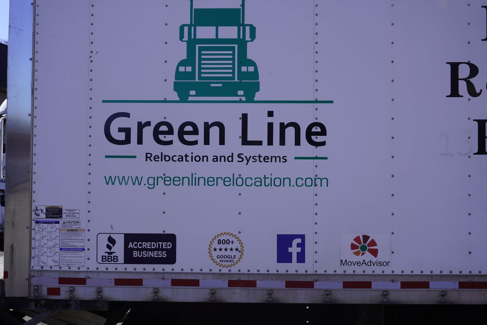 Side panel of a Green Line Relocation and Systems moving truck featuring company name, website, and business logos.