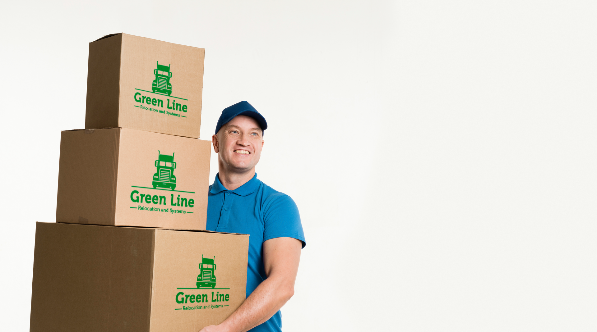Delivery person in blue uniform smiles while carrying a stack of three cardboard boxes with a green logo. White background.