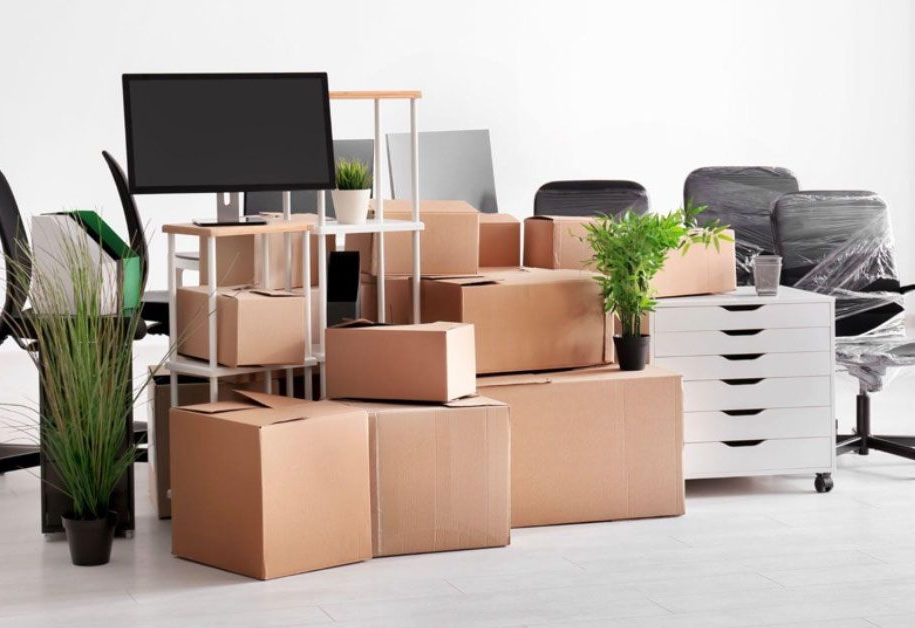 Office space with boxes, furniture, and plants prepared for a move.
