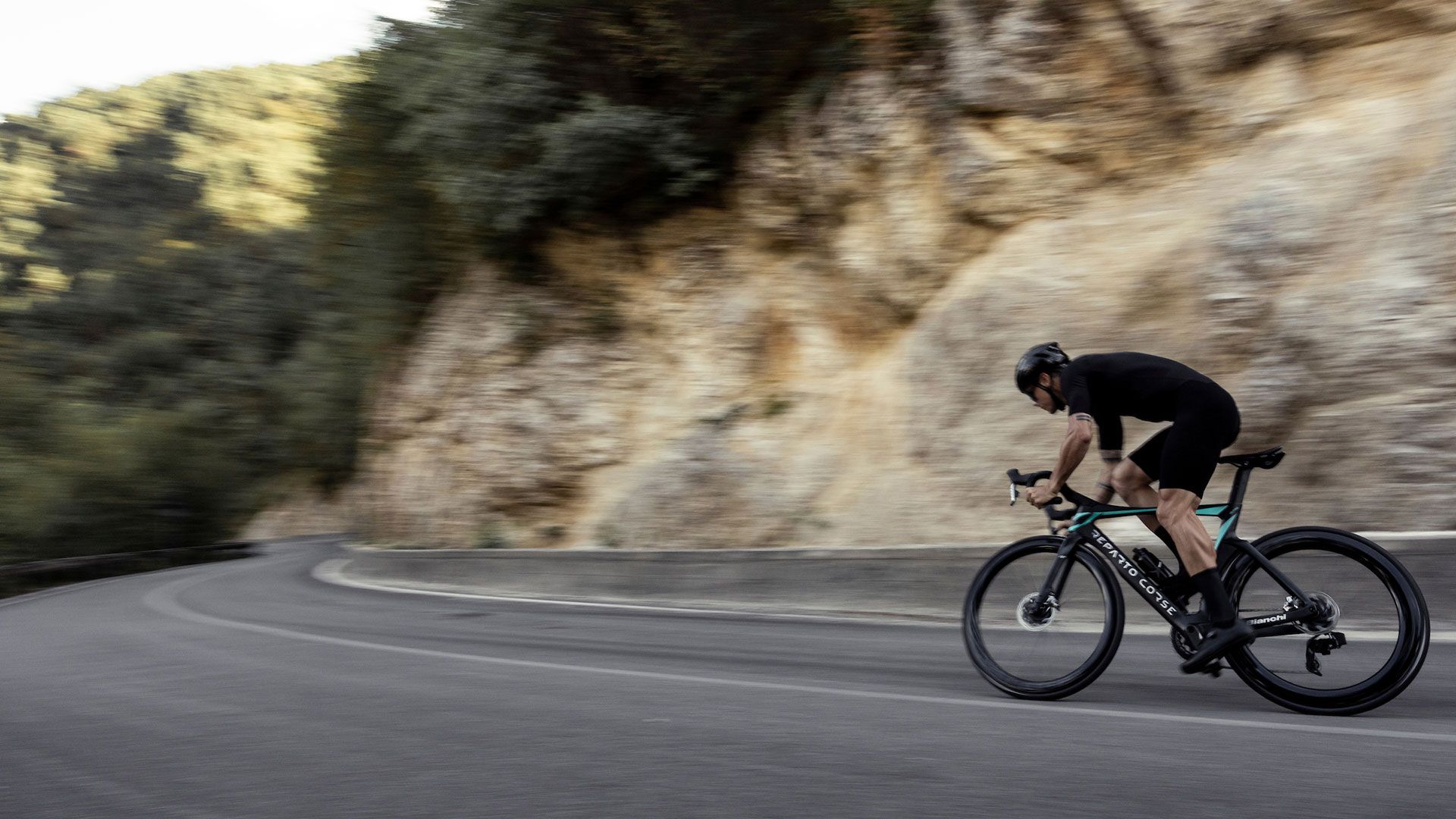 A Man Is Riding A Bicycle Down A Curvy Road — Trinity Cycle Works In Cairns City, QLD