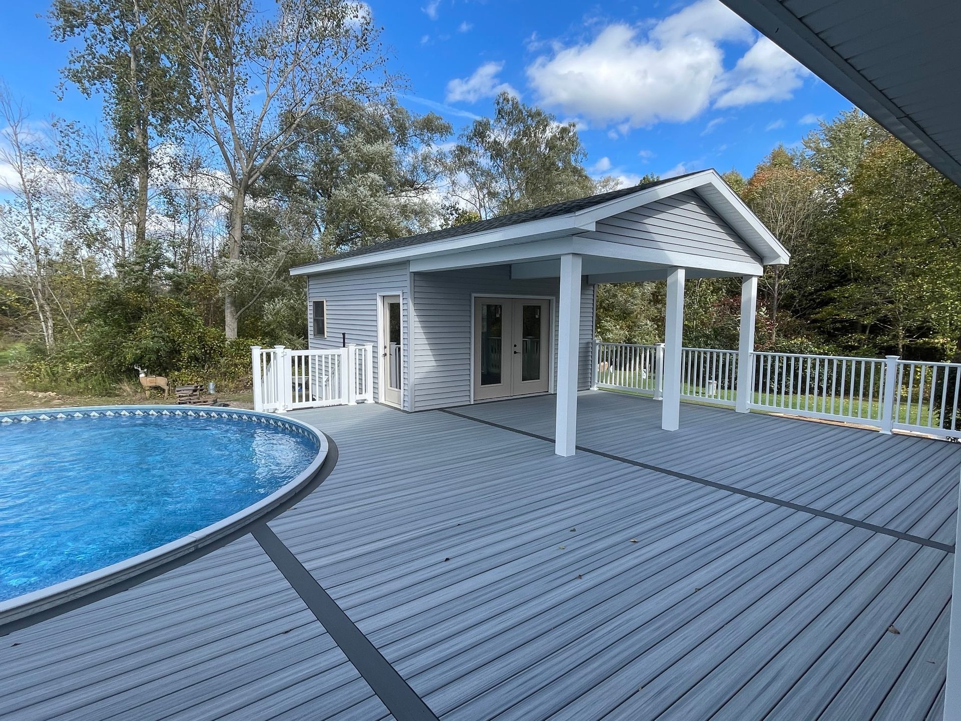 A large deck with a swimming pool and a house in the background.