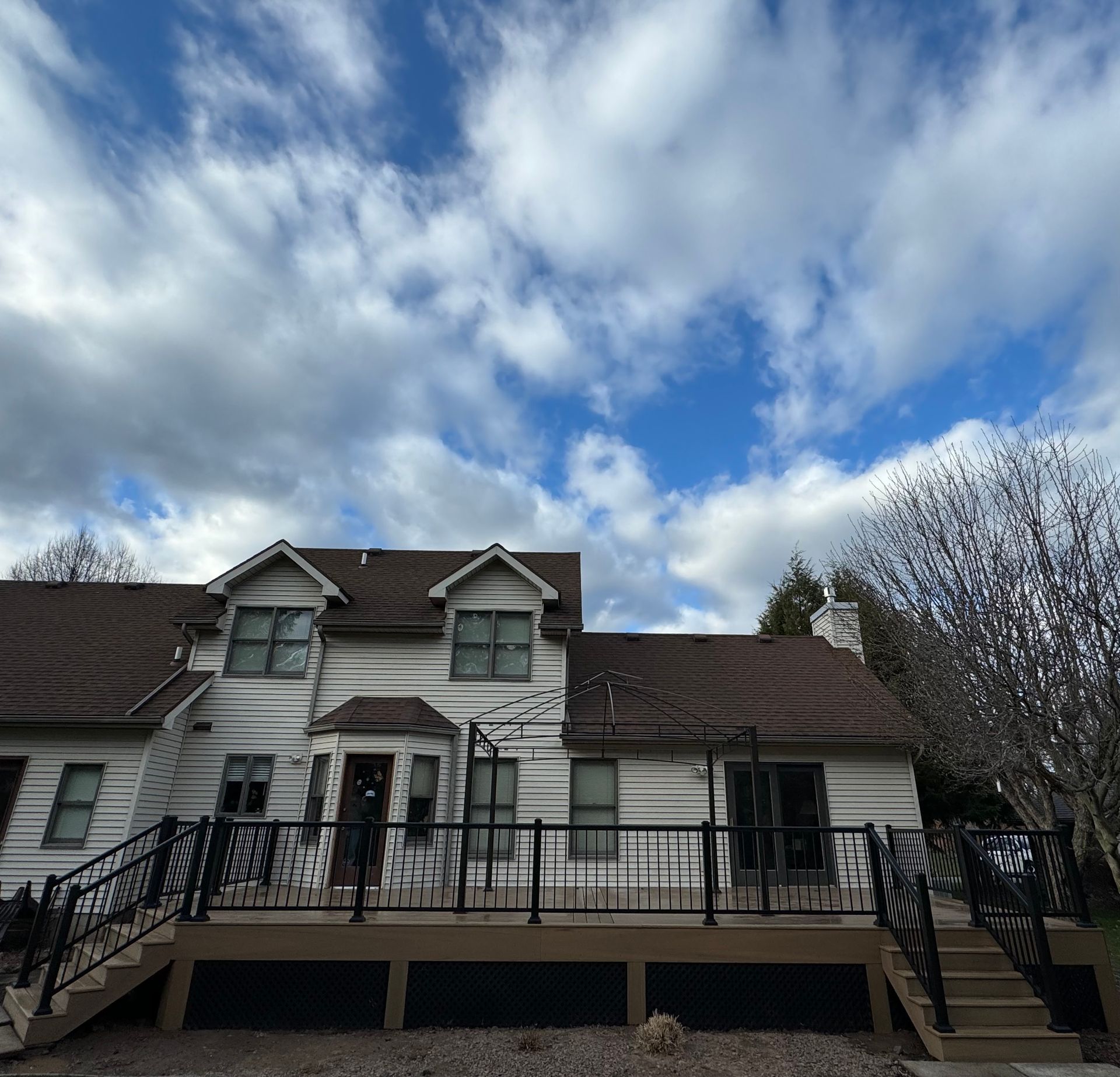 A white house with a brown roof and a deck