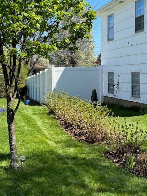 A white house with a white fence and a tree in front of it.