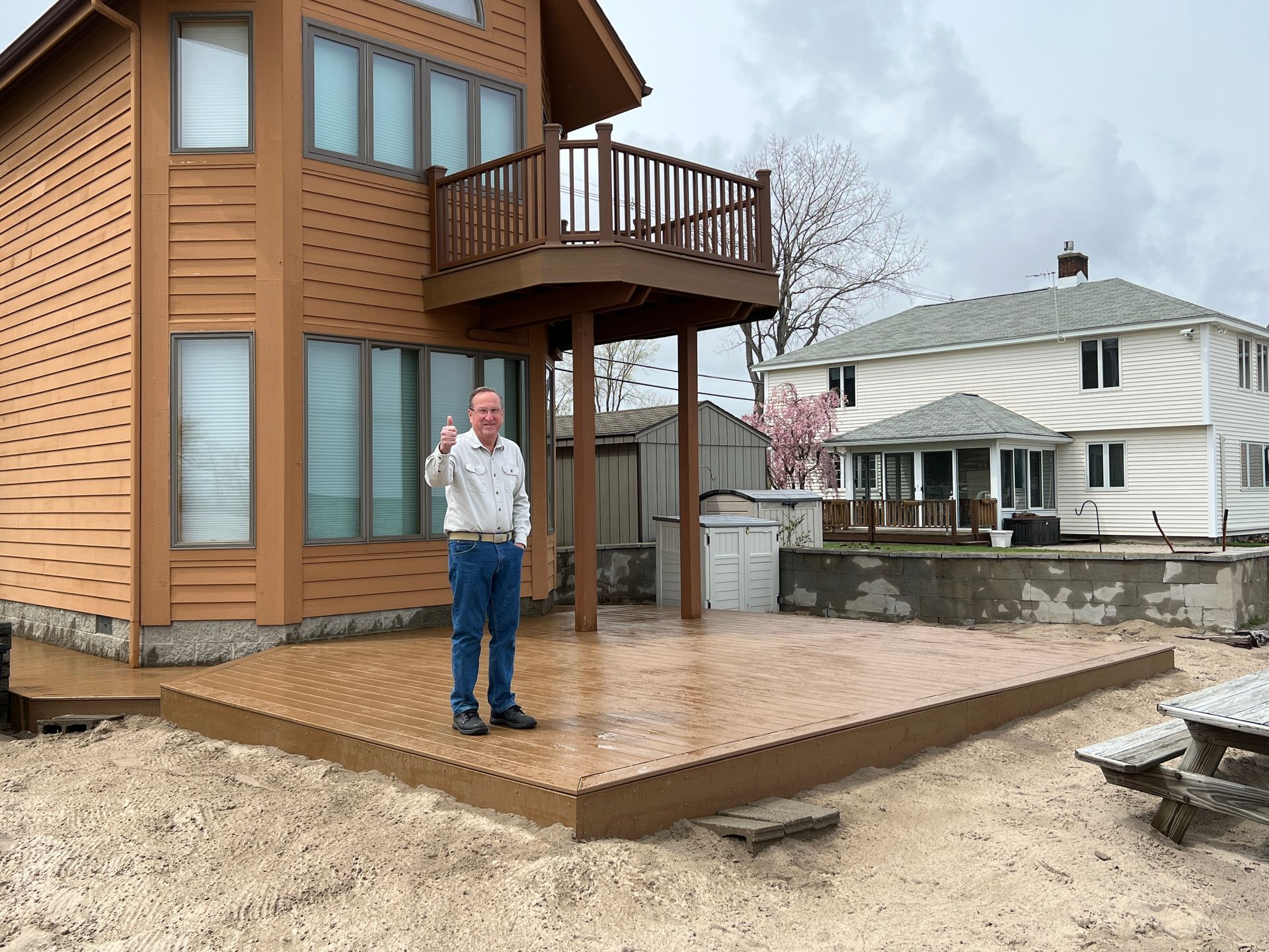 A man is standing on a deck in front of a house.