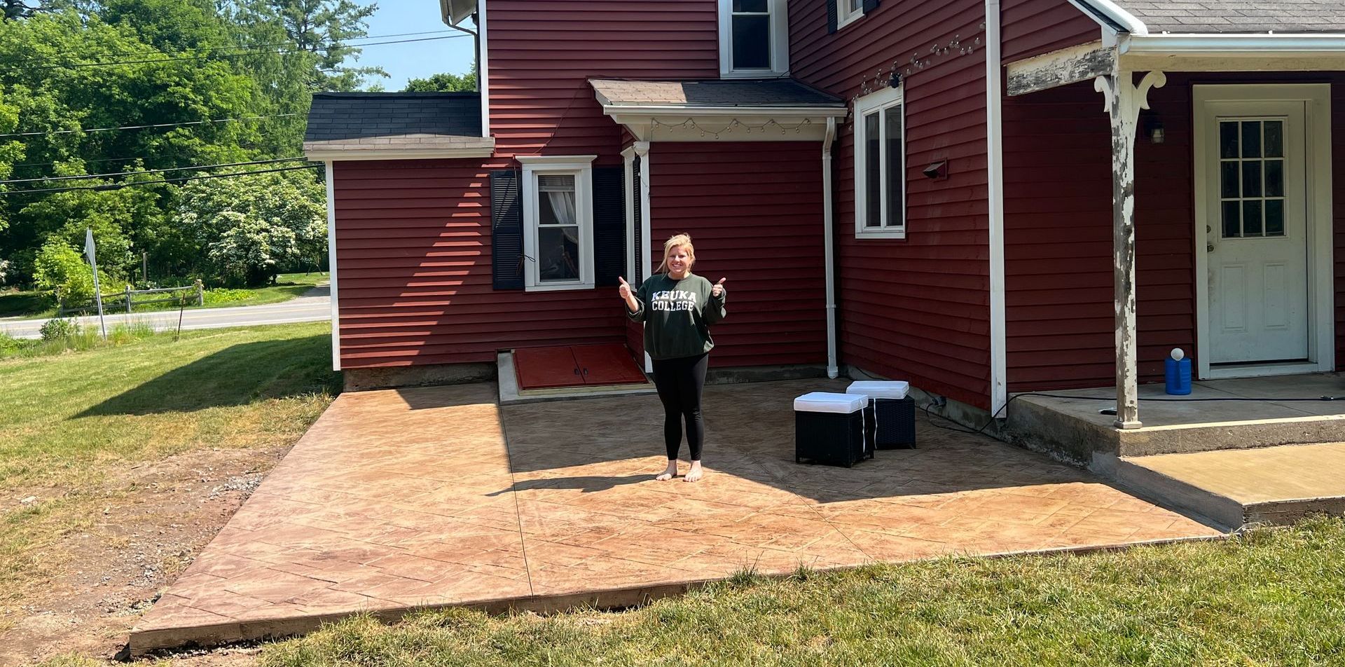 A woman is standing in front of a red house.