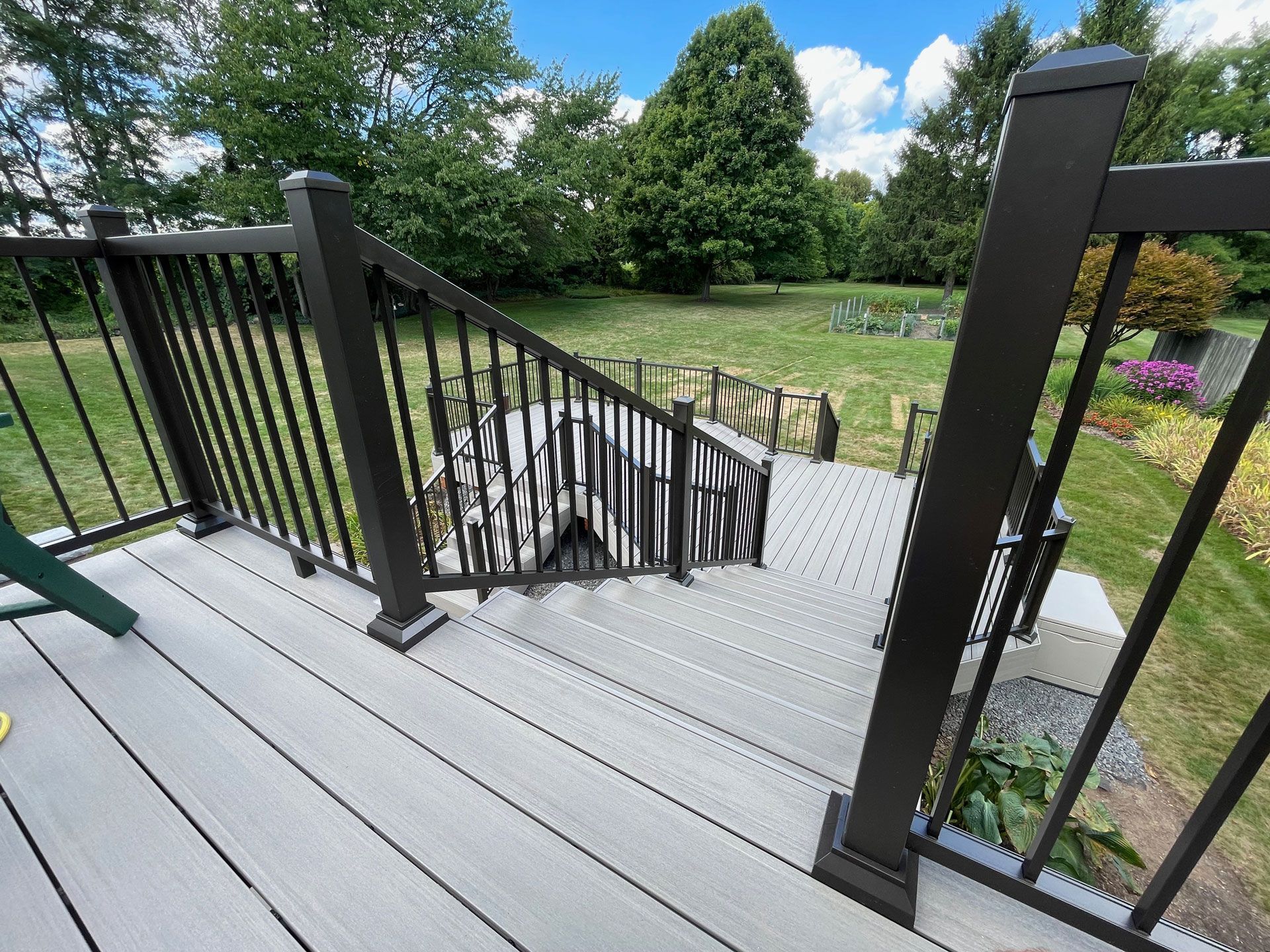 Composite deck with black railing and steps leading down to a grassy yard.