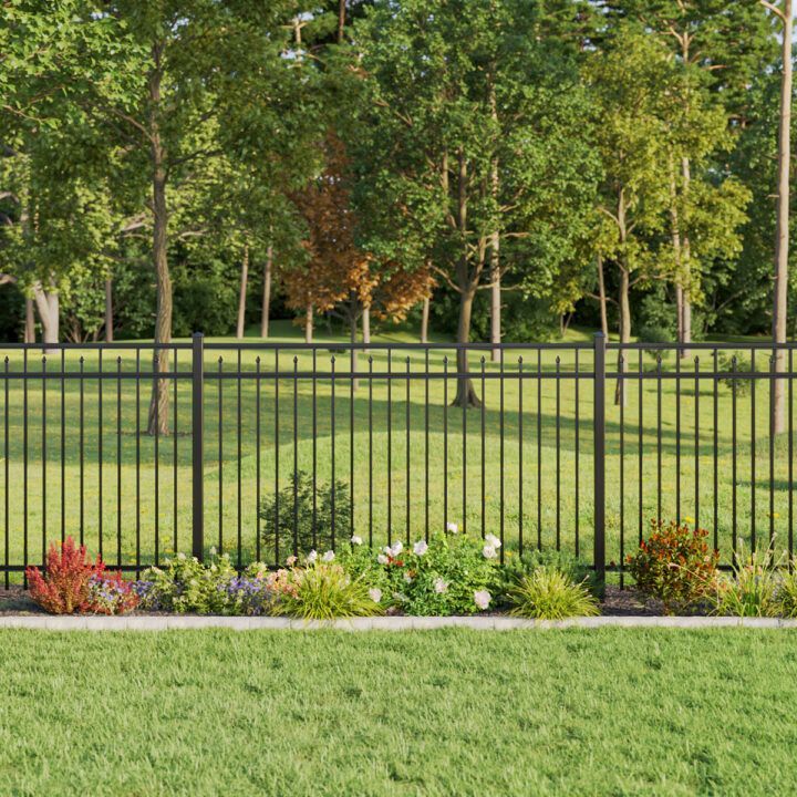 A black metal fence surrounds a lush green field with trees in the background.