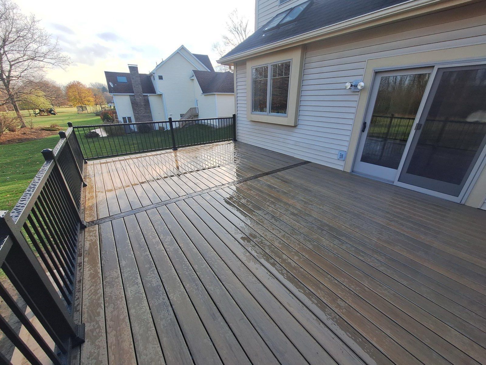 A large wooden deck in front of a house with a sliding glass door.