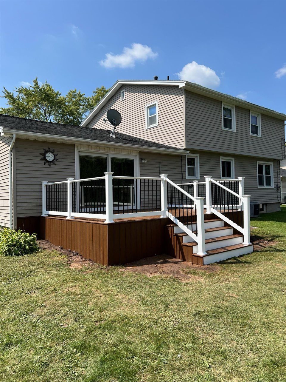 A large house with a deck and stairs in front of it.