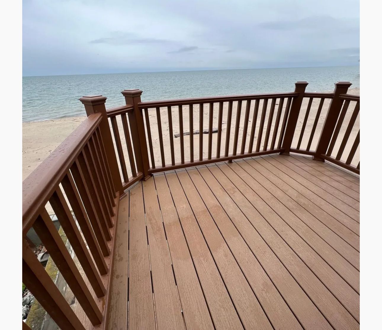 A wooden deck with a railing overlooking the ocean