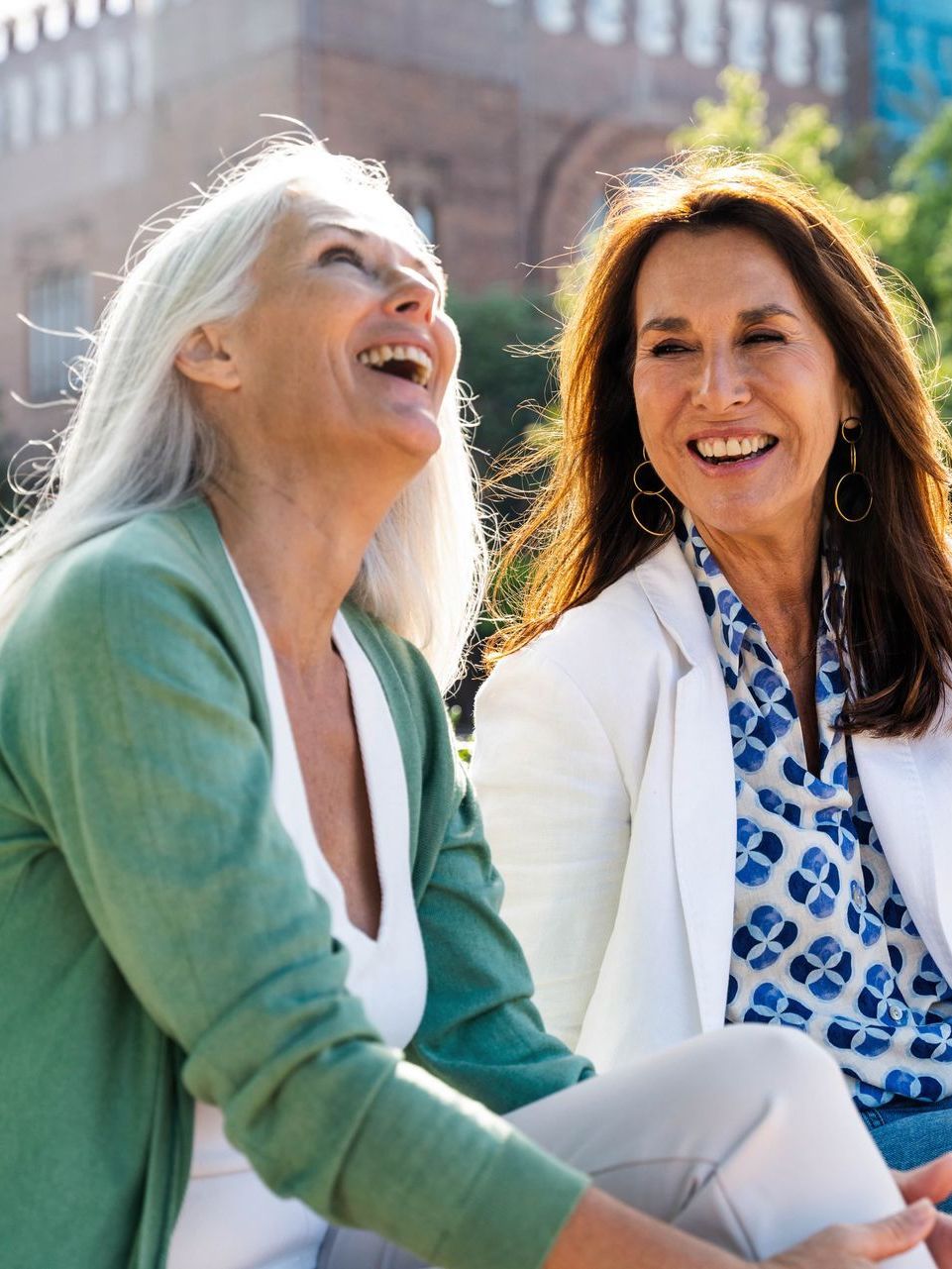 Two women are sitting next to each other and laughing.