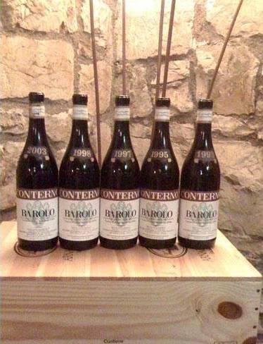 Cinque bottiglie di vino sono appoggiate sopra una scatola di legno.