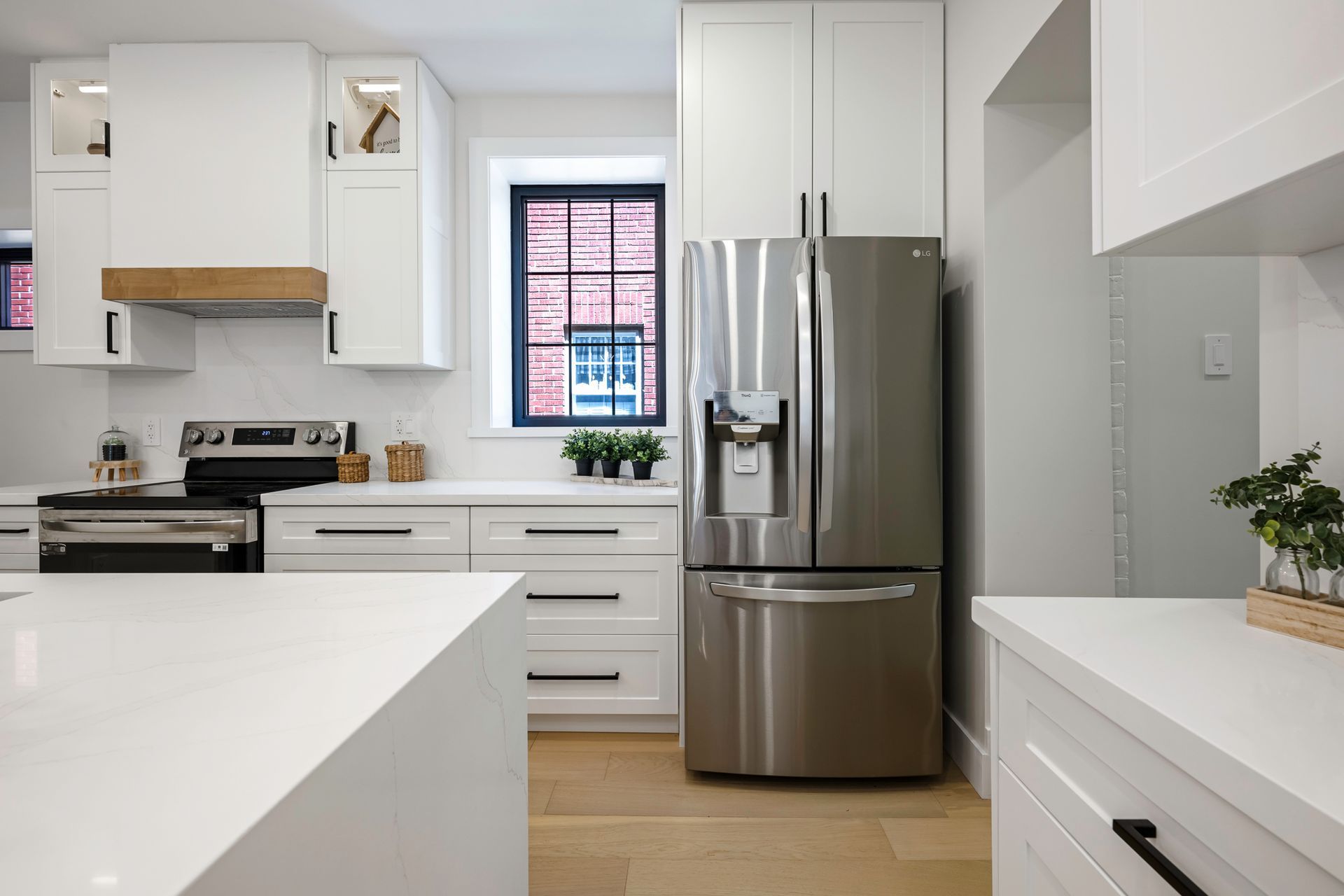 Modern white kitchen with stainless steel refrigerator, white cabinets, and a kitchen island.