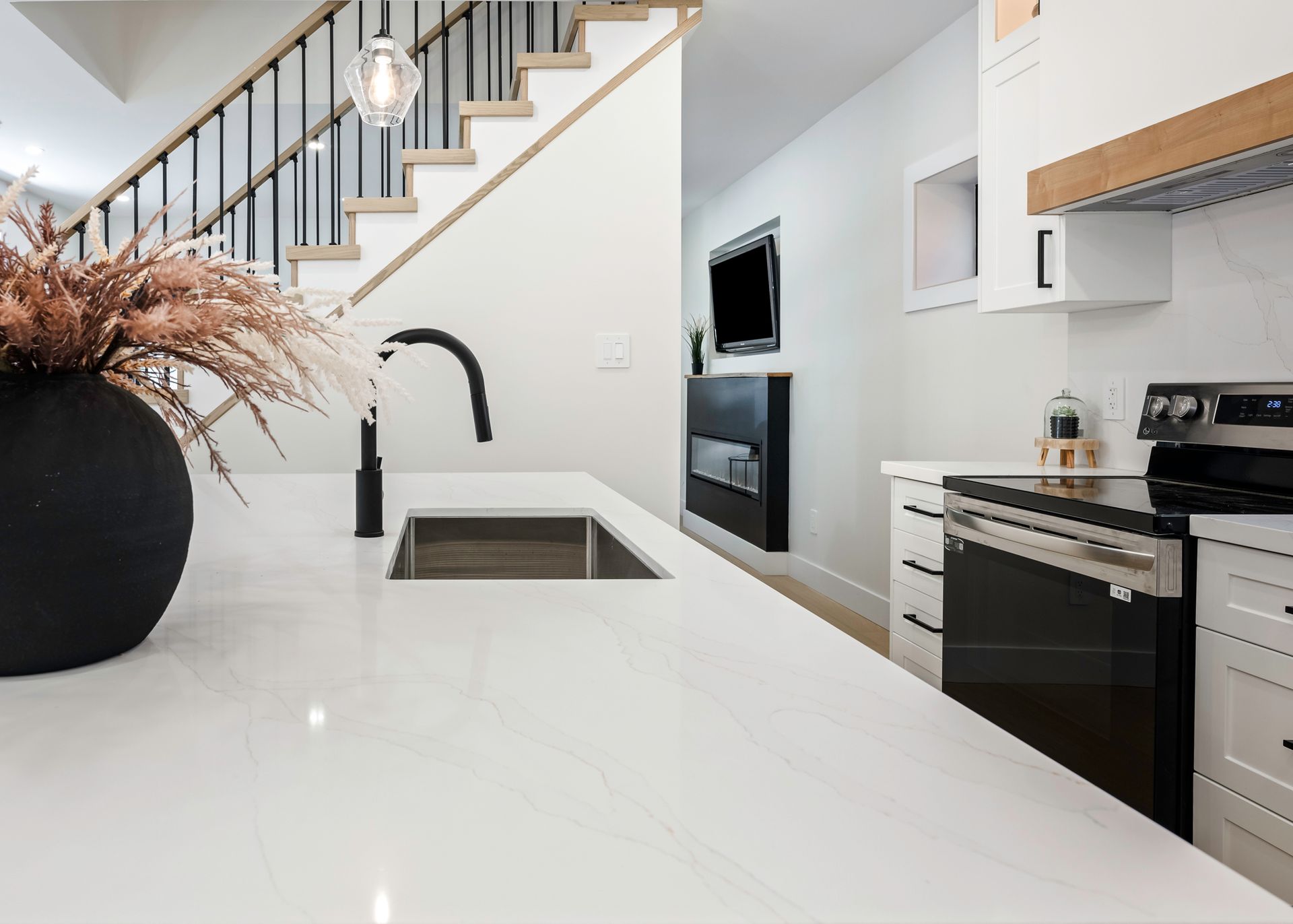 Modern kitchen with white countertop, black faucet, and stainless steel appliances.