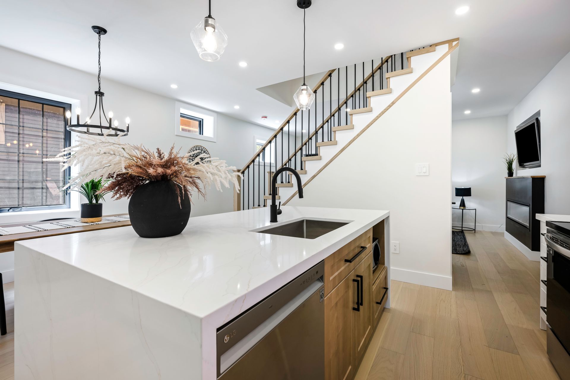 Modern kitchen with white countertops, wooden cabinets, and staircase.
