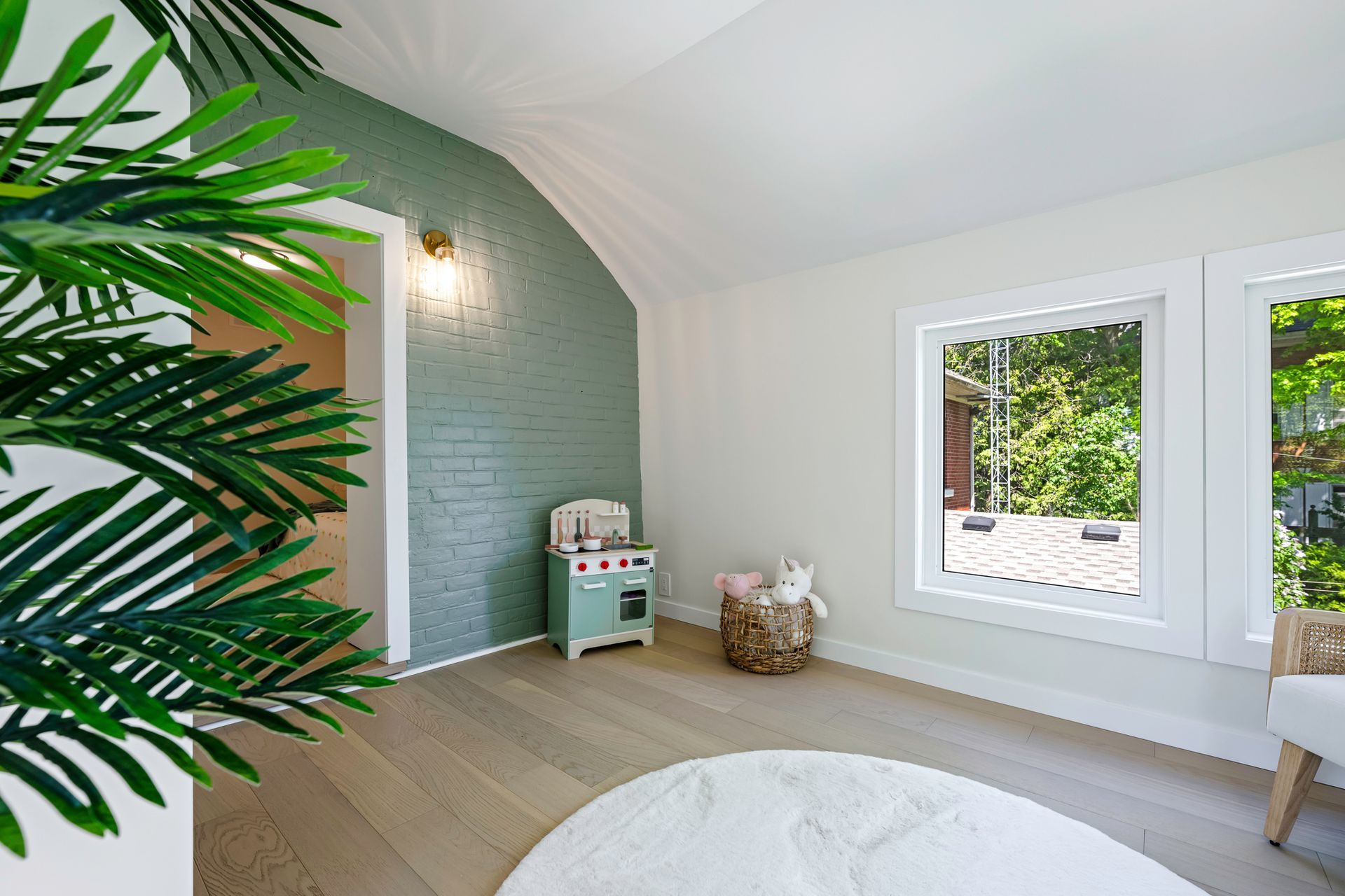 Playroom with a teal brick accent wall, toy kitchen, and round rug.