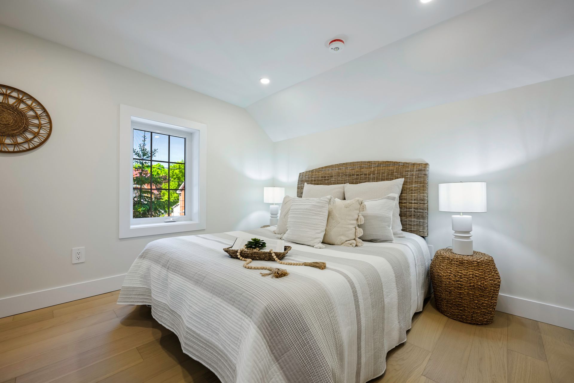 Bedroom with a neutral color scheme, wooden floor, and a bed with textured headboard and decorative pillows.