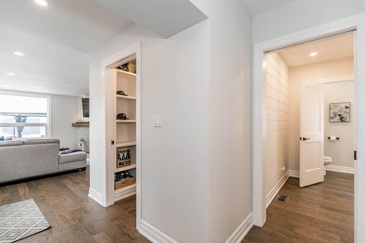 Hallway with wooden floor, leading to a pantry and a bathroom. White walls and trim, neutral tones.