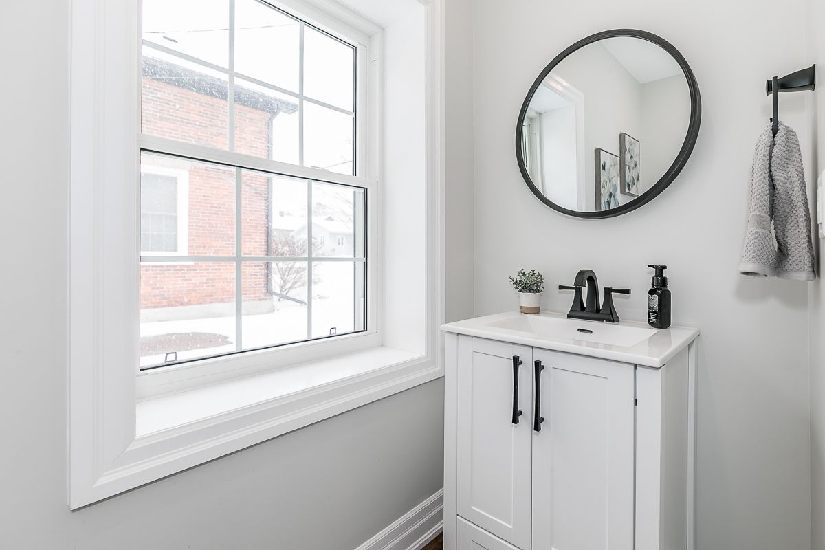 Small white bathroom with a sink, mirror, and window.