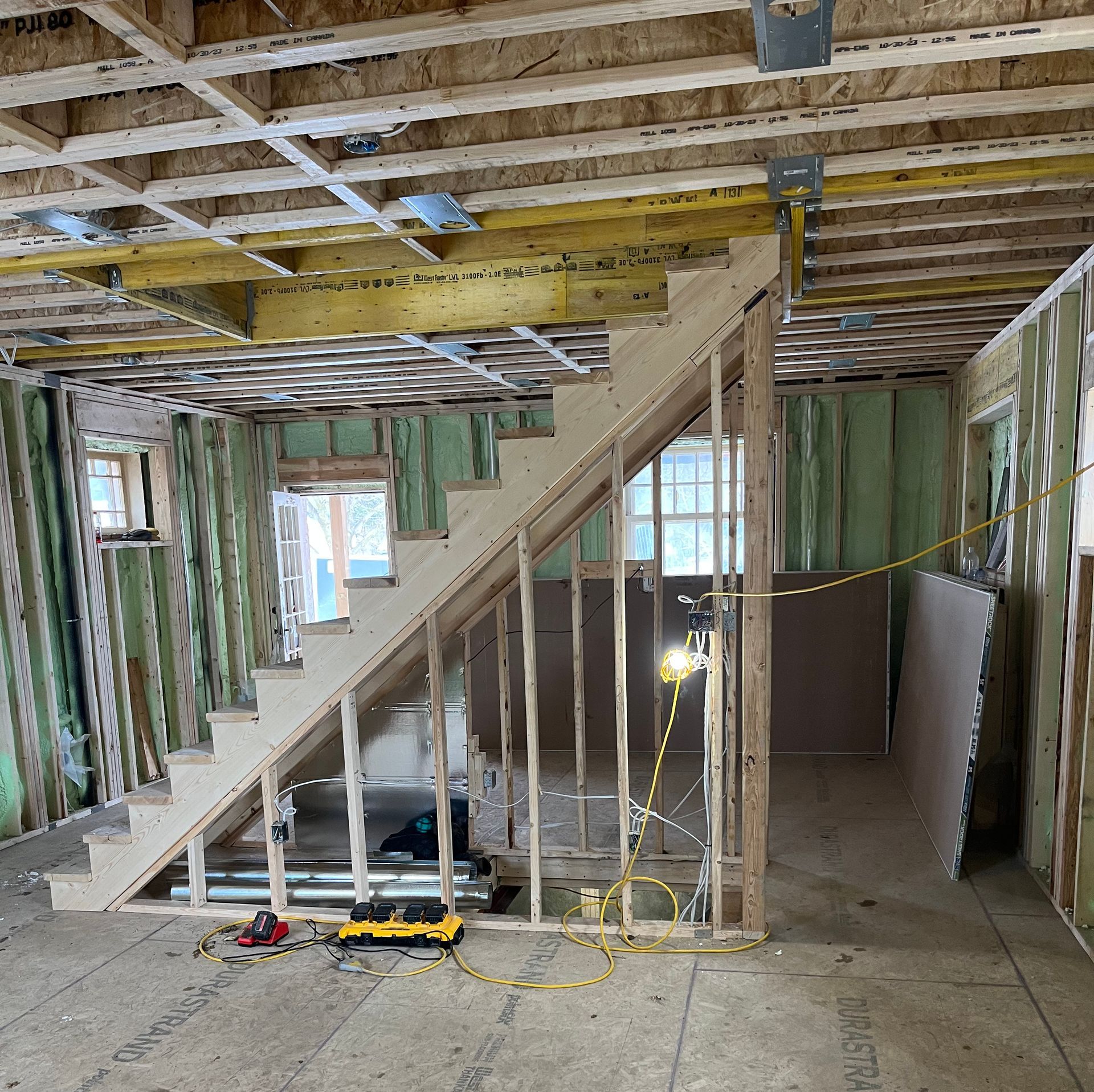 Interior view of a building under construction. Staircase and wooden framing are visible.