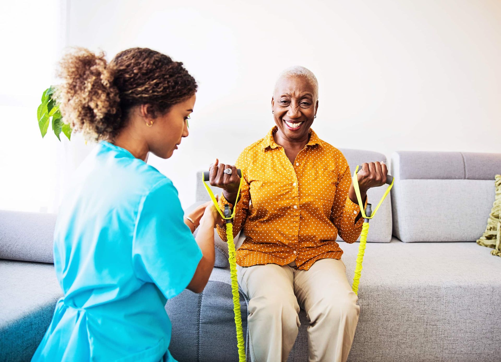 Healthcare worker assists an older adult with resistance band exercise.