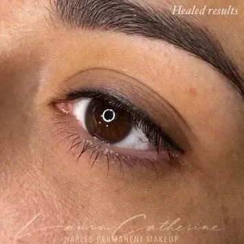 Close-up of a woman's eye with eyeliner. Dark brown eye with subtle healed permanent makeup.