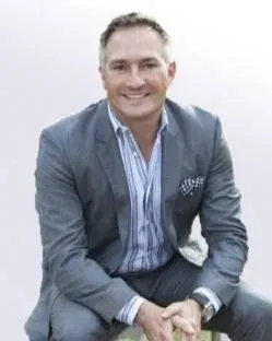 Blonde woman with fair skin and red lipstick smiles, wearing a black shirt.