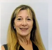 Woman with blonde hair smiling at the camera, wearing a black top, against a white background.