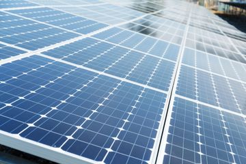 A bunch of solar panels are lined up on a roof
