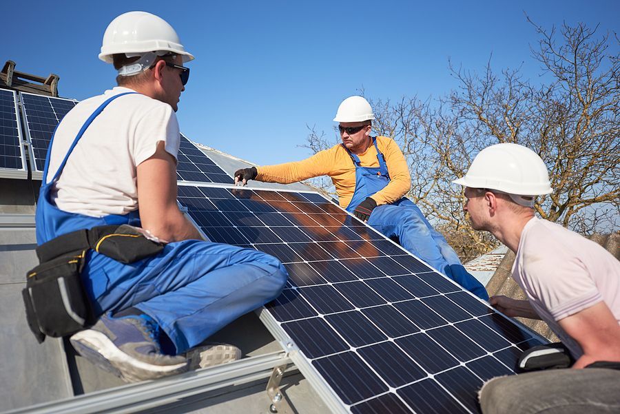 Three men are installing solar panels on a roof