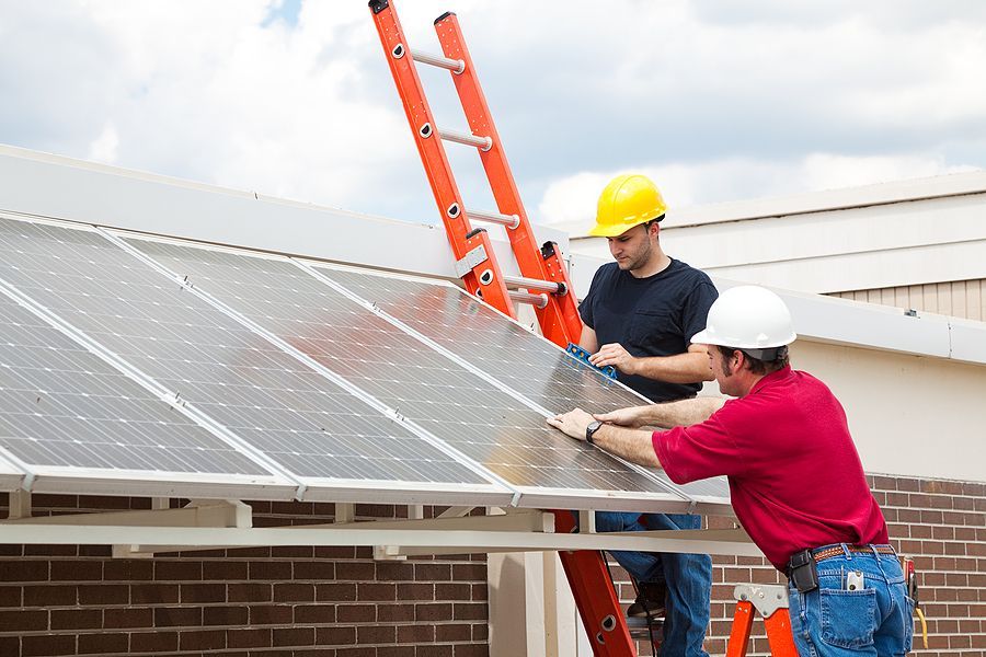 Two men are installing solar panels on the roof of a house