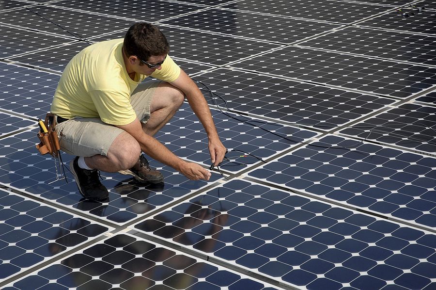 A man in a yellow shirt is working on solar panels