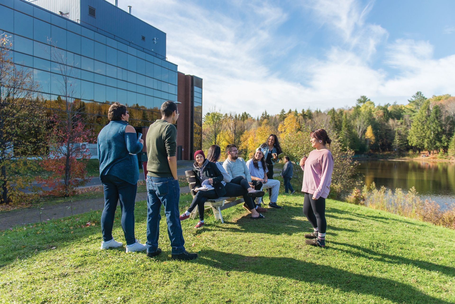 Students standing beside the pond behind campus
