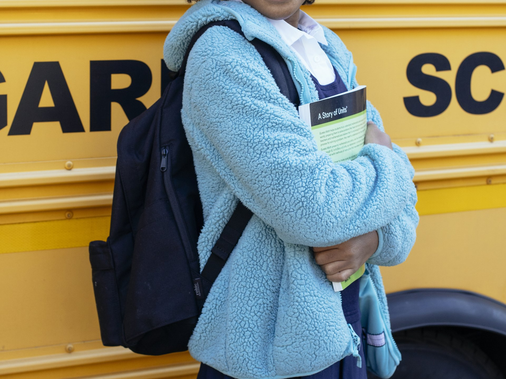 a girl standing in front of a school bus holding a book titled a story of child