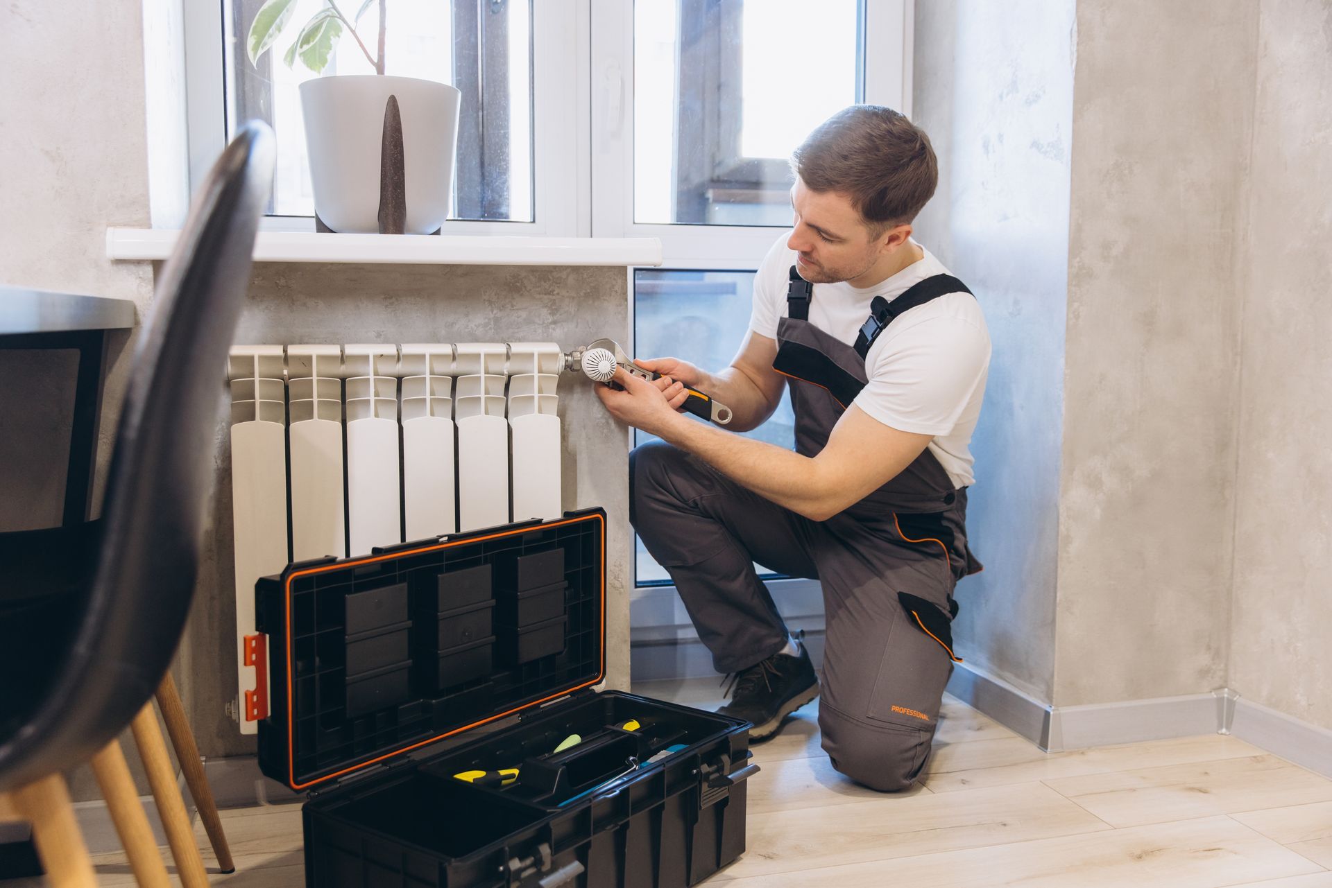 Plumber fixing thermostat valve on radiator. Plumber fixing thermostat valve on radiator.